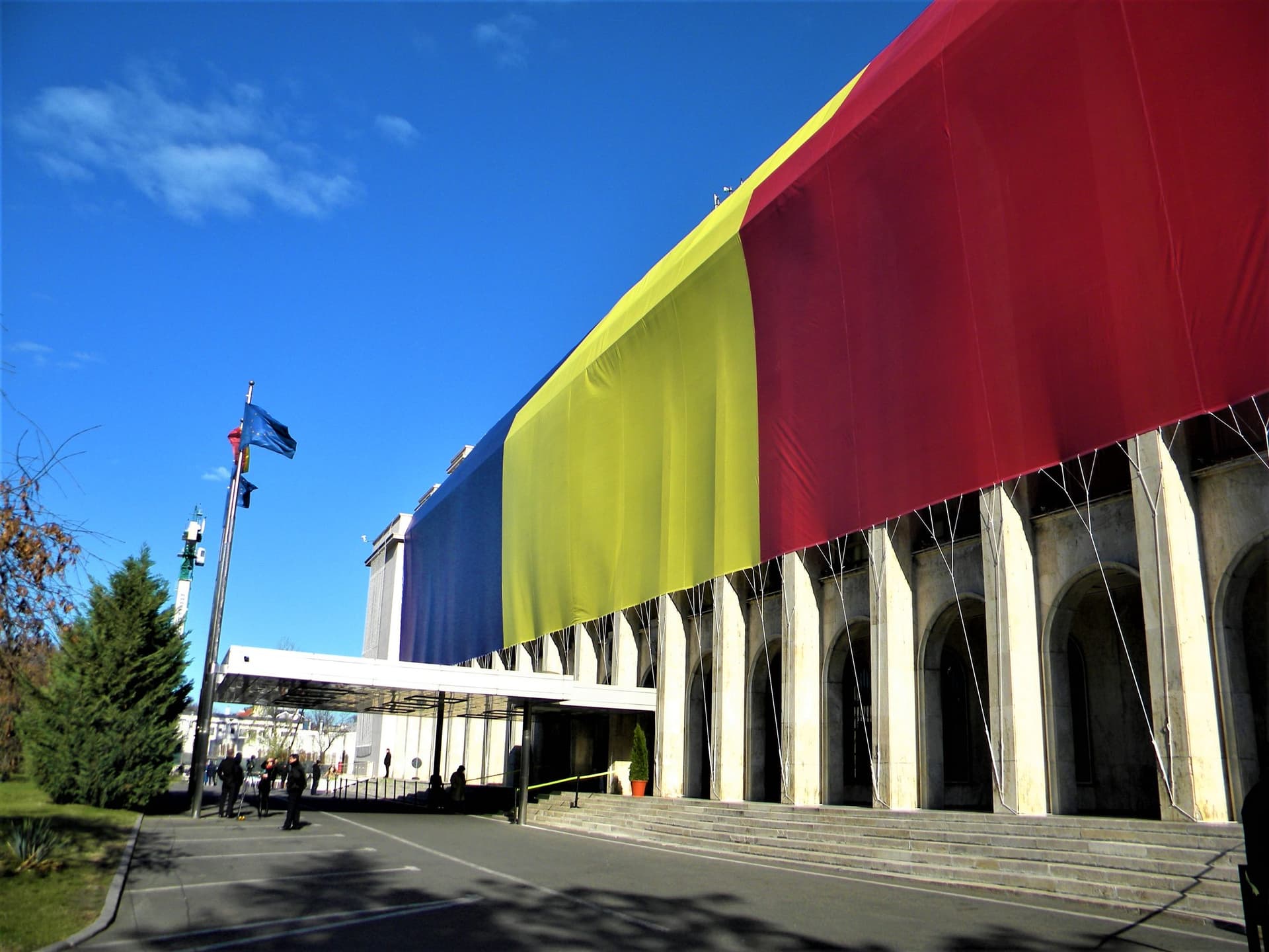 Fațada principală a Palatului Victoria din Piața Victoriei, București, sediul Guvernului României, văzută de la nivelul străzii într-o zi însorită.
