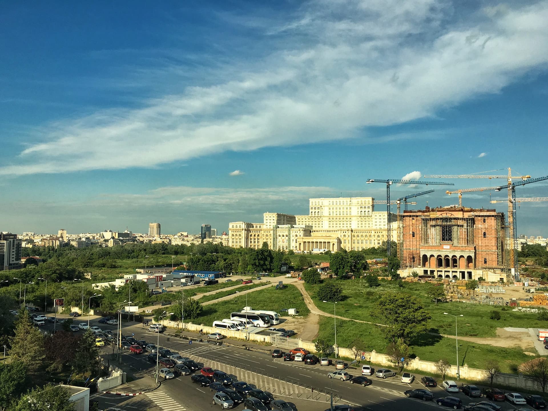 Palatul Parlamentului din București, văzut de la distanță, clădire masivă din piatră albă, sub un cer cu nori