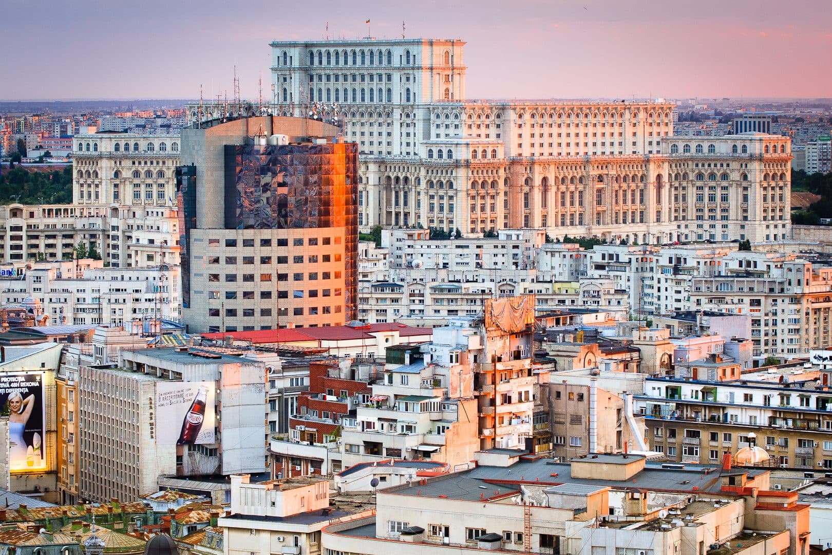 Panoramă a Bucureștiului la apus, cu Palatul Parlamentului dominând în plan îndepărtat blocurile și acoperișurile din centrul orașului.
